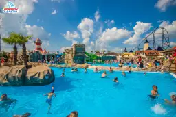 Energylandia strefa wodna tętni życiem. Ludzie kąpią się w basenie, bawią na zjeżdżalniach, a w tle widać rollercoaster.
