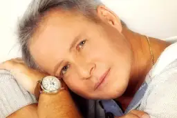 Portret mężczyzny z siwymi włosami, w okrągłej bransoletce z brązowym paskiem.