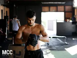 Mężczyzna w rękawicach MMA w siłowni.