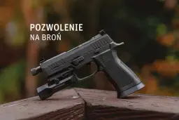 Czarny pistolet z latarką na drewnianym blacie, z napisem "POZWOLENIE NA BROŃ".