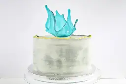 Tort z ozdobą z błękitnego karmelu w kształcie eksplozji.