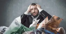 Zmartwiony mężczyzna w garniturze tonie w banknotach euro. Czy delegacja podlega zajęciu komorniczemu?
