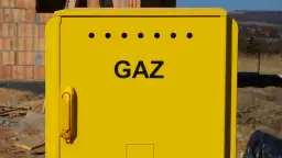 Żółta skrzynka gazowa na budowie. Zastanawiasz się, ile kosztuje przyłącze gazu od skrzynki do domu?