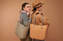 Dwie kobiety prezentują modne torebki na lato. Jedna w beżowym swetrze, druga w brązowym kapeluszu.