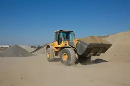 Żółta ładowarka Volvo z pełną łyżką ziemi. Posiadanie uprawnień na koparko ładowarki klasa 1 to klucz do obsługi takich maszyn.