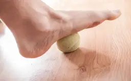 Stopień z zapaleniem rozcięgna podeszwowego objawy: masaż stopy piłeczką tenisową łagodzi ból.