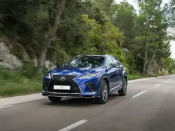 Niebieski Lexus RX 450h jedzie po krętej drodze wśród zieleni.