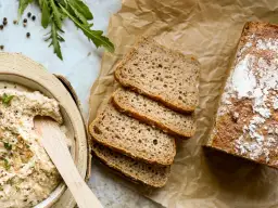 Chleb żytni, pokrojony w kromki, obok miski z pastą. Czy żyto ma gluten? Tak, żytnie pieczywo zawiera gluten.