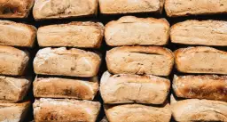 Stos chleba, który zastanawia, czy pies może jeść chleb. Każdy bochenek ma złocistą skórkę i lekko posypany mąką.