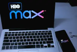 Logo HBO Max na ekranie laptopa i smartfona, obok słuchawki.