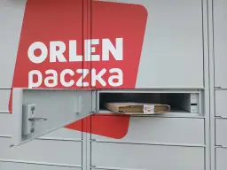 Szafka paczkomatu z logo Orlen Paczka i paczką w środku.