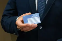Mężczyzna trzyma Europejską Kartę Ubezpieczenia Zdrowotnego. Ważność karty EKUZ jest kluczowa dla podróżujących po Europie.