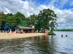Plaża i jezioro w Szczecinku, z budynkami gastronomicznymi i ludźmi na wodzie. Idealne miejsce na letnie atrakcje.