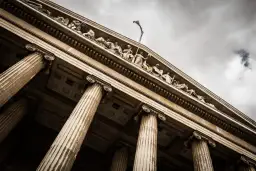 Klasycystyczny budynek sądu z kolumnami i rzeźbami na fasadzie.