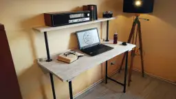 Stylowe biurko z palet, z laptopem, książką i okularami, dopełnione lampą i radiem retro.