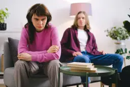 Smutna kobieta siedzi obok mężczyzny, czując ciężar trudnych relacji, jakby doświadczyła wpływu toksycznego ojca.