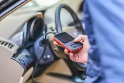 Diagnostyka Renault: ręka trzyma skaner OBD, który może pomóc rozwiązać problem DTC B1267.