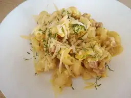 Pyszna carbonara z cukinią, makaronem, boczkiem i parmezanem, posypana świeżym koperkiem.