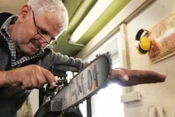 Mężczyzna z okularami majstruje przy pile, pokazując, jak skrócić łańcuch do piły domowym sposobem.