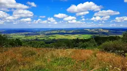 Widok z tokarnia szczyt na zielone wzgórza, pola i wiatraki pod błękitnym niebem z chmurami.