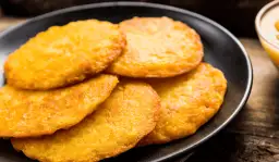 Złociste placki ziemniaczane na czarnym talerzu.