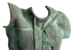 Fragment rzeźby z brązu przedstawiający tors z zieloną patyną.