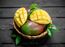 Koszyk z dojrzałymi mango, jedno przekrojone w kostkę. Czy zastanawiałeś się nad mango indeks glikemiczny?