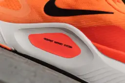 Pomarańczowe buty sportowe z systemem wsparcia śródstopia, idealne dla biegaczy potrzebujących stabilizacji i zapobiegających nadmiernej pronacji.