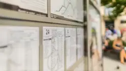 Rozkład jazdy autobusów Kraków. Widoczne tablice z godzinami odjazdów, mapka linii i ludzie czekający na przystanku.