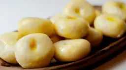 Ugotowane kluski śląskie z wgłębieniem, ułożone na drewnianej desce.