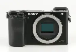 Czarny aparat Sony a6000, gotowy do testów. Widoczny obiektyw E-mount i sensor APS-C.