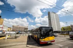 Żółto-czerwony autobus miejski na tle wieżowca Novotel i budynków w Warszawie. Może to być przystanek na trasie autobus warszawa kaliningrad.