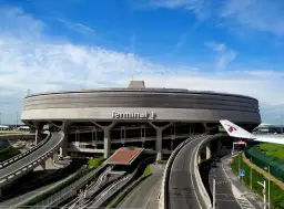 Terminal 1 na lotnisku Paryż-Charles de Gaulle, z charakterystyczną, okrągłą architekturą i drogami prowadzącymi do niego.