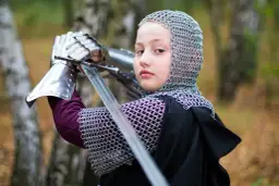 Dziecko w zbroi kolczej i z mieczem, przygotowujące się do walki.