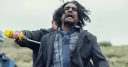 Mężczyzna w garniturze krzyczy, gdy ktoś trzyma go za rękę z żółtym przedmiotem. Scena z serialu "Tęsknię za tobą".