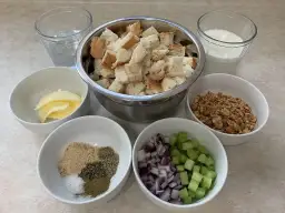 Składniki do farszu: pokrojony chleb, masło, cebula, seler, orzechy, przyprawy, mleko i woda.