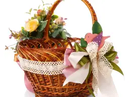 Wielkanocny koszyczek ozdobiony kwiatami, koronką i wstążkami. Uroczy drewniany ptaszek dodaje uroku. Idealny przykład, jak ozdobić koszyczek wielkanocny wstążką.