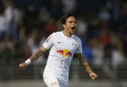 Piłkarz w białej koszulce z logo Red Bull świętuje bramkę. Wśród najlepszych brazylijskich piłkarzy, jego radość jest zaraźliwa.