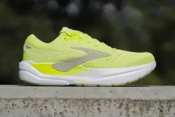 Jaskrawożółte buty Brooks Ghost Max, jedne z najdroższych butów do biegania, na betonowym murku.