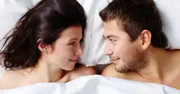 Para młoda leży w łóżku, patrząc na siebie z czułością. Czy to ich seks na pierwszej randce?