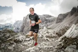 Andrzej Długosz biegnie po kamienistym szlaku w górach, pokonując trudny teren.