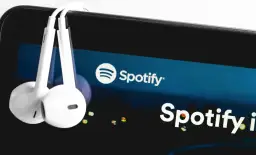 Słuchawki wiszące na ekranie smartfona z logo Spotify.
