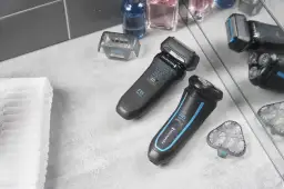 Dwie golarki elektryczne Remington R6 Wet/Dry, akcesoria i kosmetyki na szarym blacie.