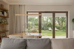 Nowoczesne wnętrze z widokiem na ogród. Zamiast karnisza, zasłony wiszą na szynie ukrytej w suficie, tworząc minimalistyczny efekt.