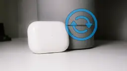 Białe etui AirPods z niebieską ikoną resetowania.