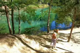 Dwie dziewczynki w słomkowych kapeluszach idą ścieżką nad turkusowe jezioro. Idealne miejsce, gdzie w góry z dziećmi na letnią przygodę.