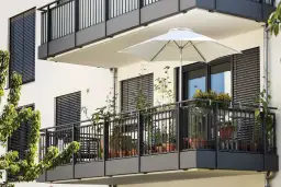 Nowoczesny balkon w bloku z roślinami w doniczkach i białym parasolem. Inspiracja, jak wykończyć balkon w bloku, by był funkcjonalny i estetyczny.