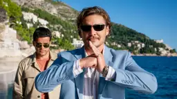 Pedro Pascal w błękitnej marynarce, z dłońmi złożonymi w geście, jakby zapowiadał kolejne z jego filmów i seriali.
