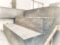 Betonowe schody w trakcie budowy. Widać surowe stopnie i ściany, gotowe do wykończenia. To pierwszy etap, jak wylać schody.