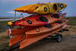 Stos kajaków na przyczepie, gotowych do spływu.
